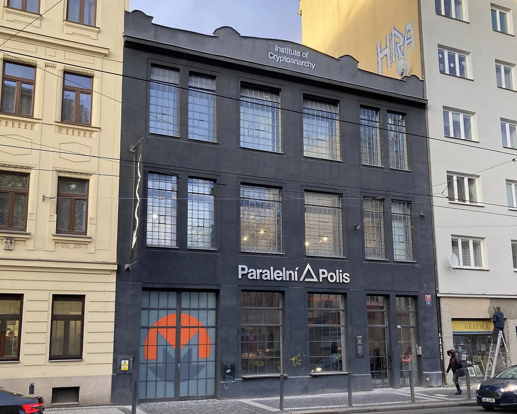 The black facade of Paralelní Polis on Dělnická street in Prague, with 'Institute of Cryptoanarchy' lettered along the roofline